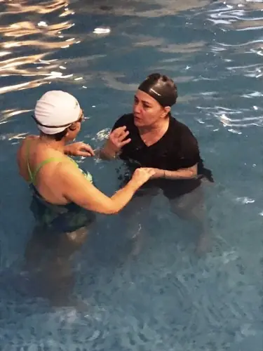 An instructor guiding a swimmer with hands on her shoulders