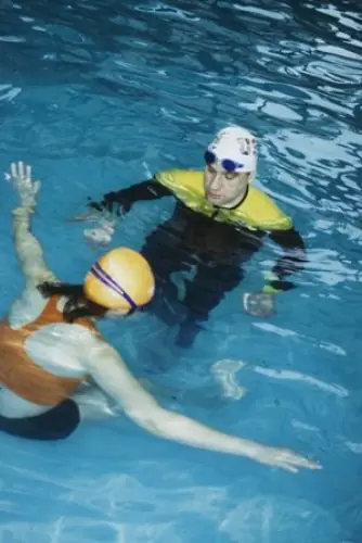 Instructor and student underwater, the student in a yellow wetsuit top